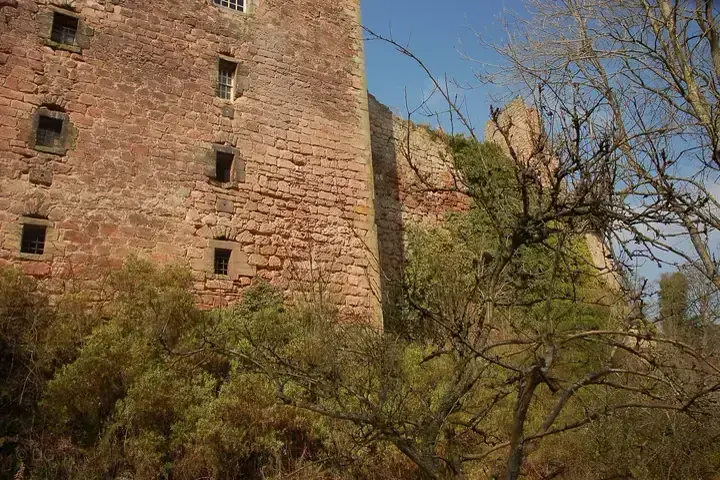 High stone facade of Roslin Castle seen through bare branches