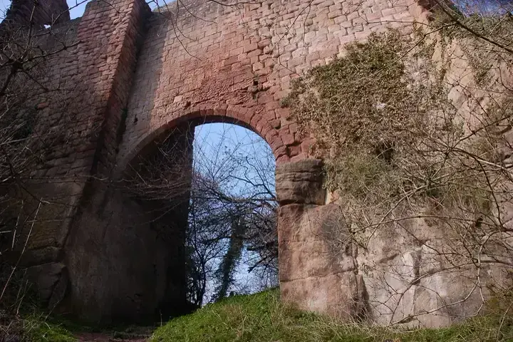Tall arch in Roslin Castle's red stone wall viewed from below