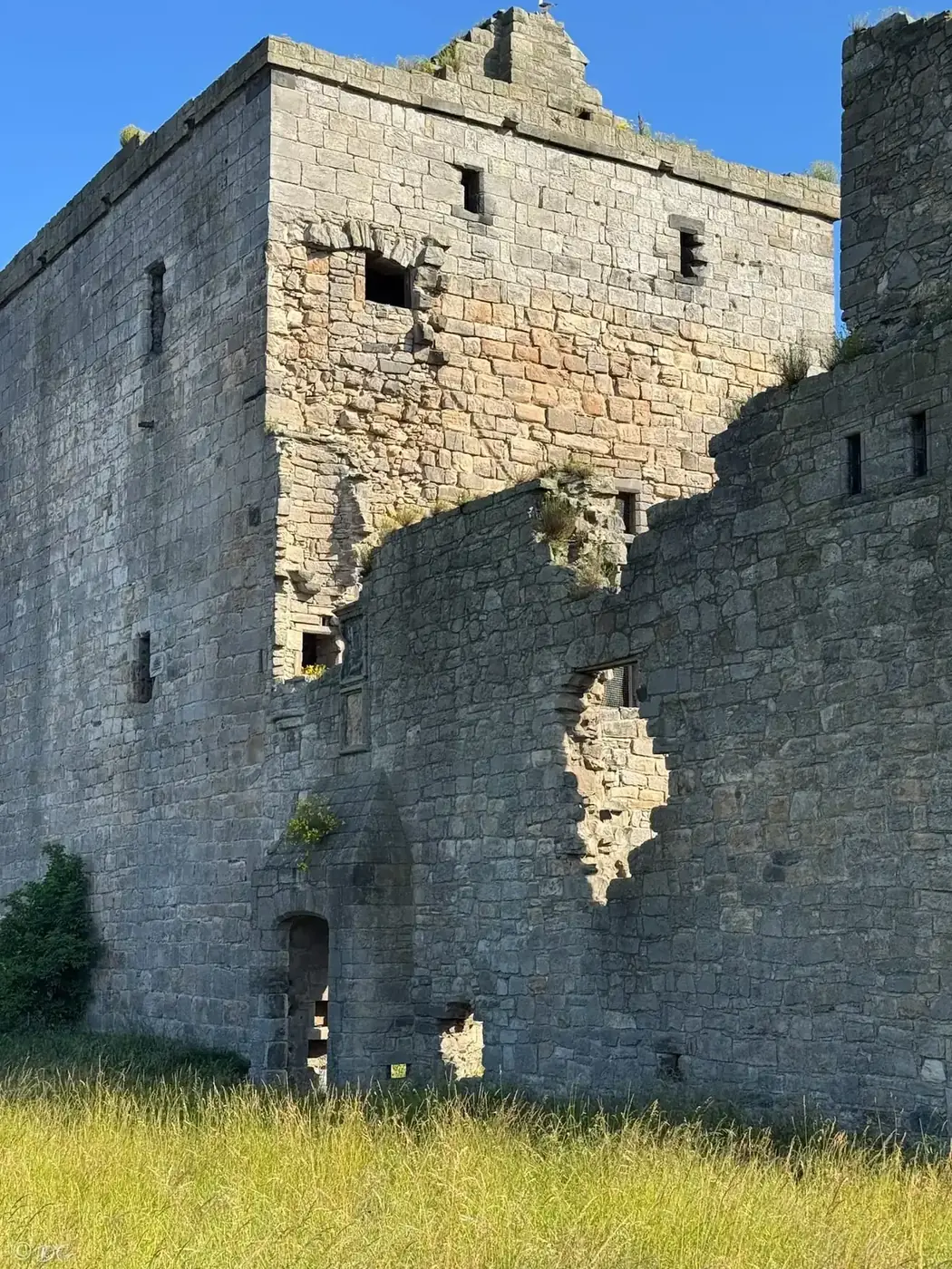 Sunlight and shadows on Rosyth Castle's tower and broken adjoining wall