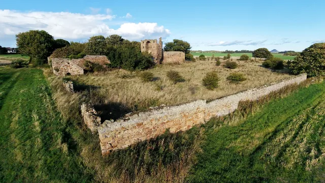 Saltcoats Castle's long boundary walls enclosing an overgrown grassy area