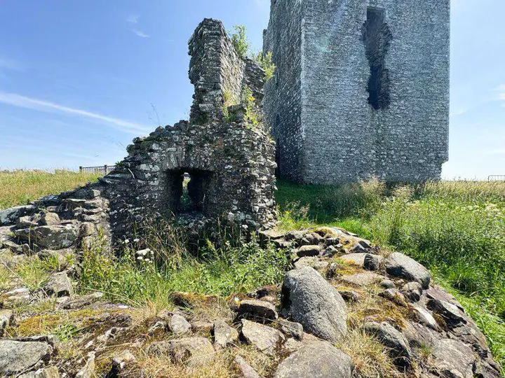 Low ruined walls and an opening at the foot of Threave Castle tower