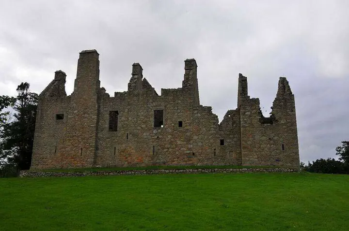 Tolquhon Castle roofless exterior walls and chimney stacks under grey clouds