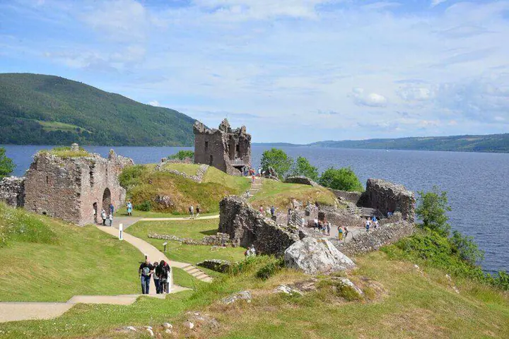 Urquhart Castle ruins and visitors overlooking Loch Ness